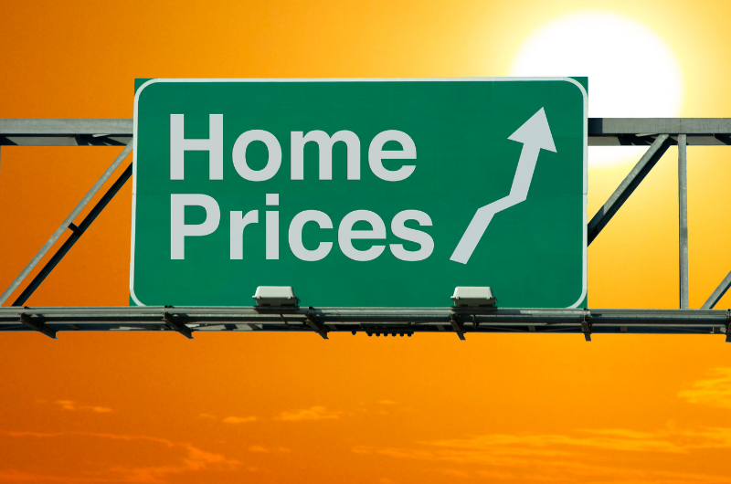 Highway sign in front of sunset reading that there is an increase in home prices