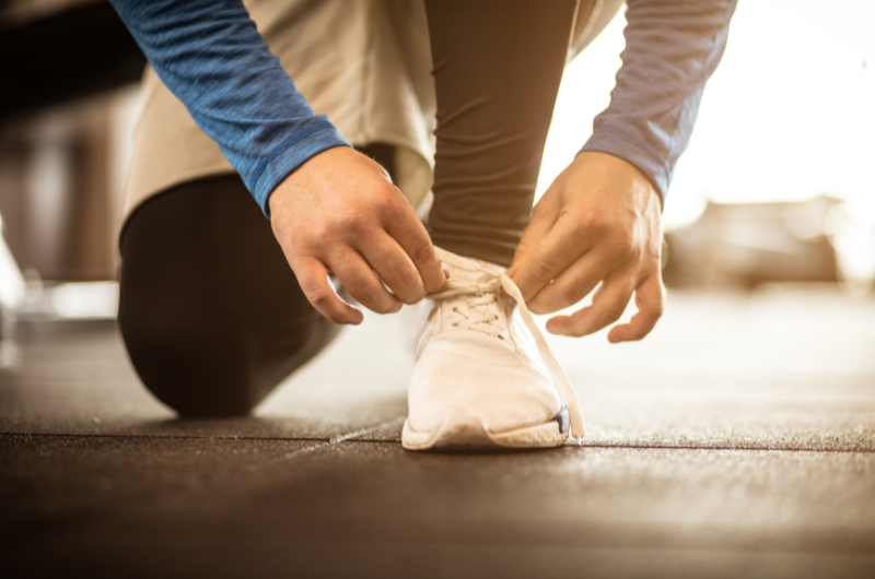 Person on one knee tying their sneaker.