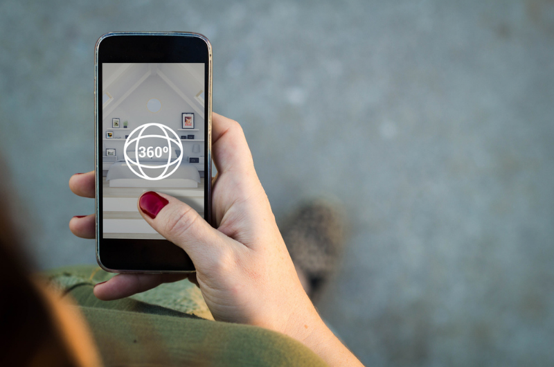 Woman's hand holding an iphone showing an image of a virtual home tour